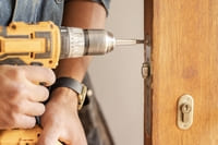 A handyman drilling to fix a door